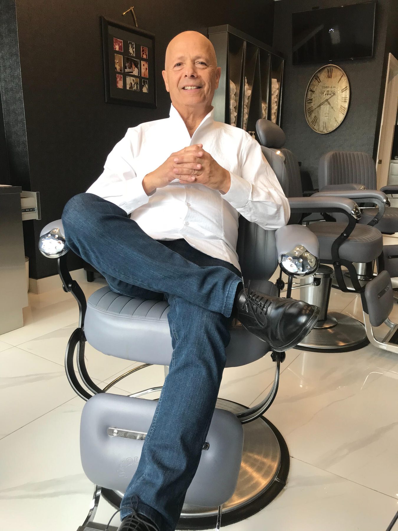 Eli, owner of Old School Barber, seated in a vintage barber chair inside the Eglinton Avenue shop