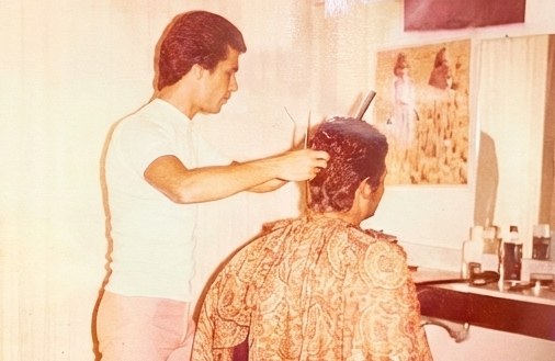 Eli trimming a client's hair while the client wears a paisley robe